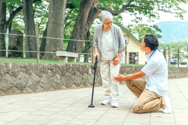 高齢者をサポートする男性スタッフ（杖）